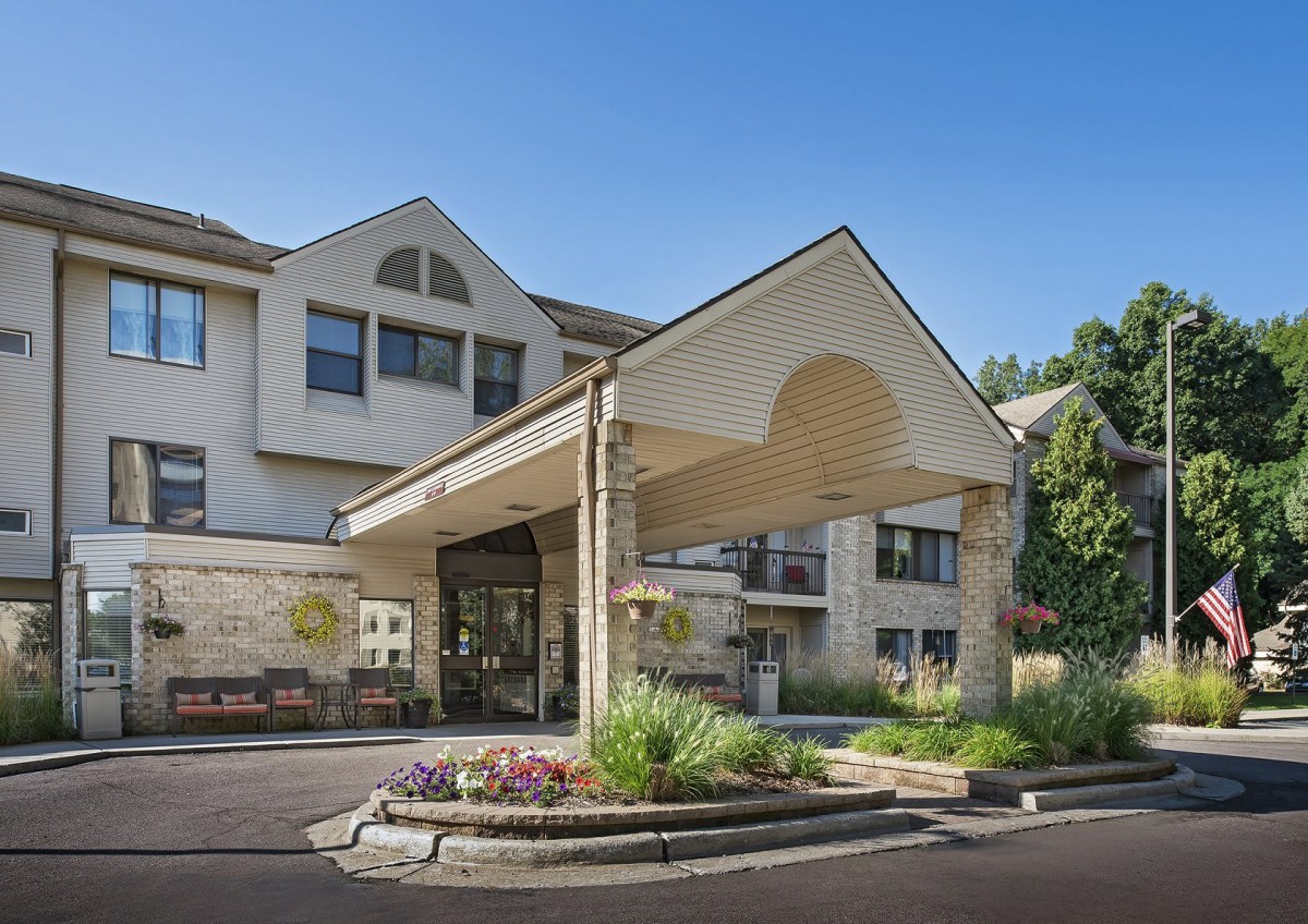 An exterior view of a building entrance with landscaping and clear blue sky.