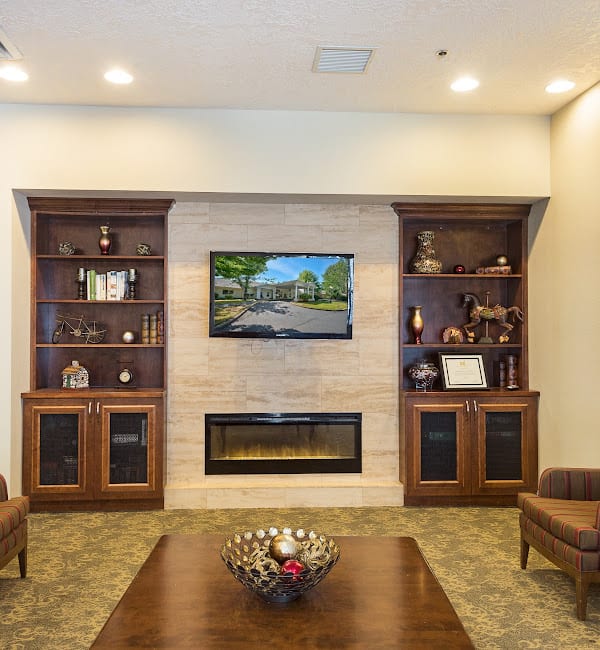 Cozy living room featuring a central fireplace, built-in bookshelves, and a mounted television.