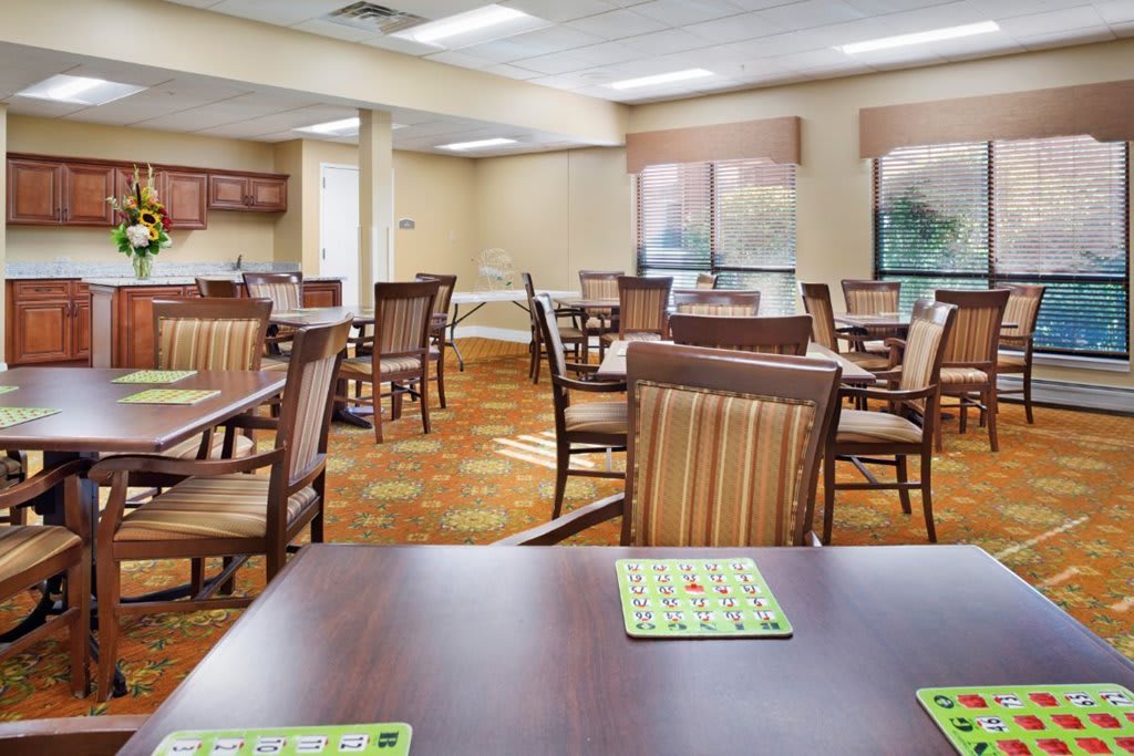 A spacious dining area with neatly arranged tables and chairs, complemented by large windows.