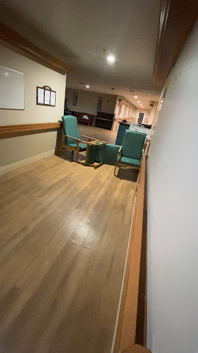 A quiet hallway featuring green chairs in a waiting area.