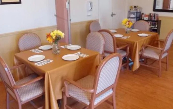 A neatly arranged dining area with tables set for guests, featuring floral centerpieces.