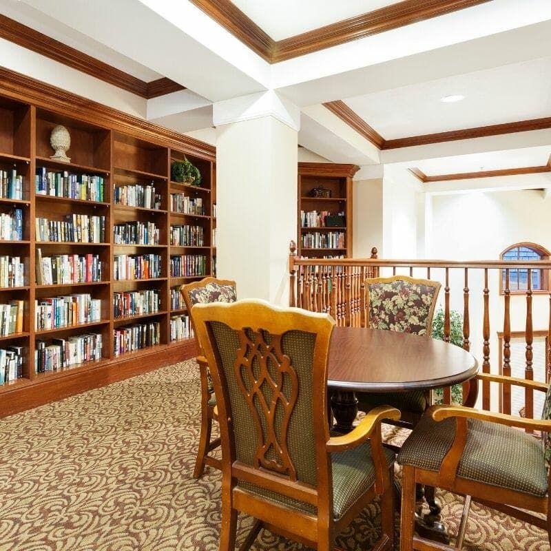 A cozy library corner with bookshelves, a table, and chairs for reading.