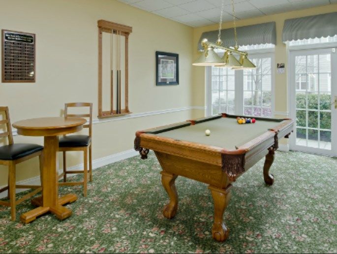 A cozy game room featuring a pool table, stylish lighting, and comfortable seating.