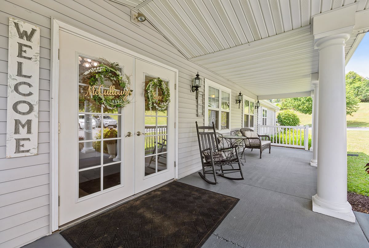 A welcoming porch with rocking chairs and decorative wreaths on the doors.