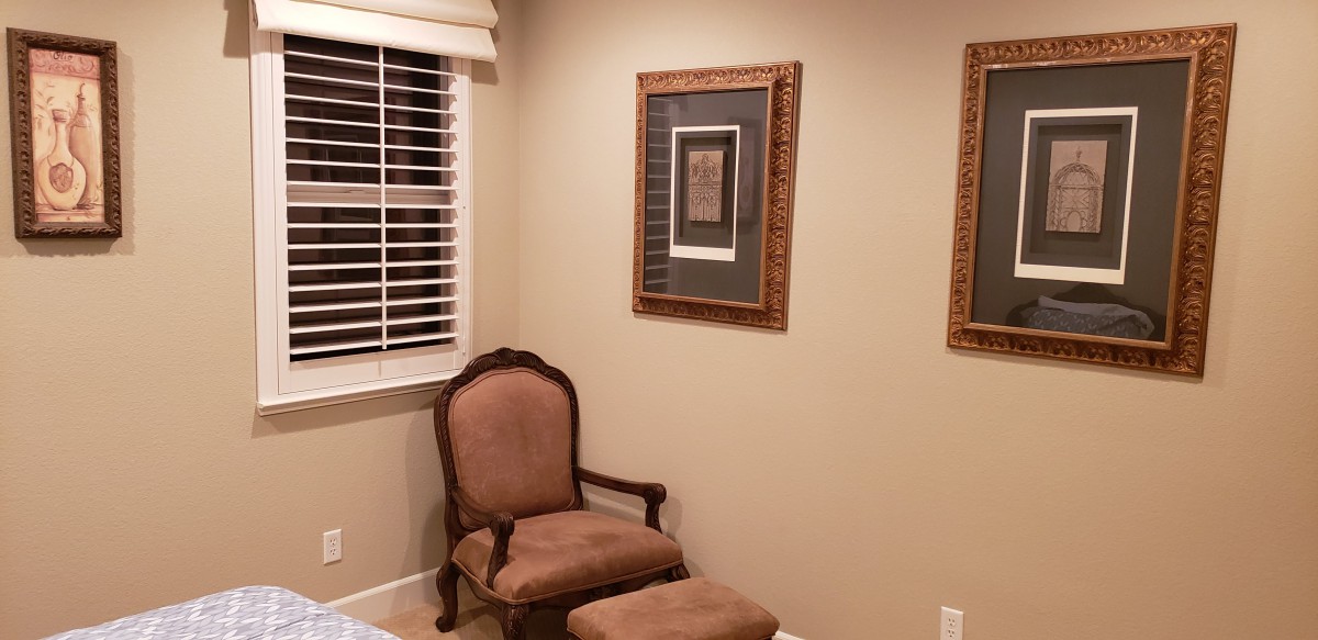 A cozy corner with a classic chair and framed artwork on the wall.