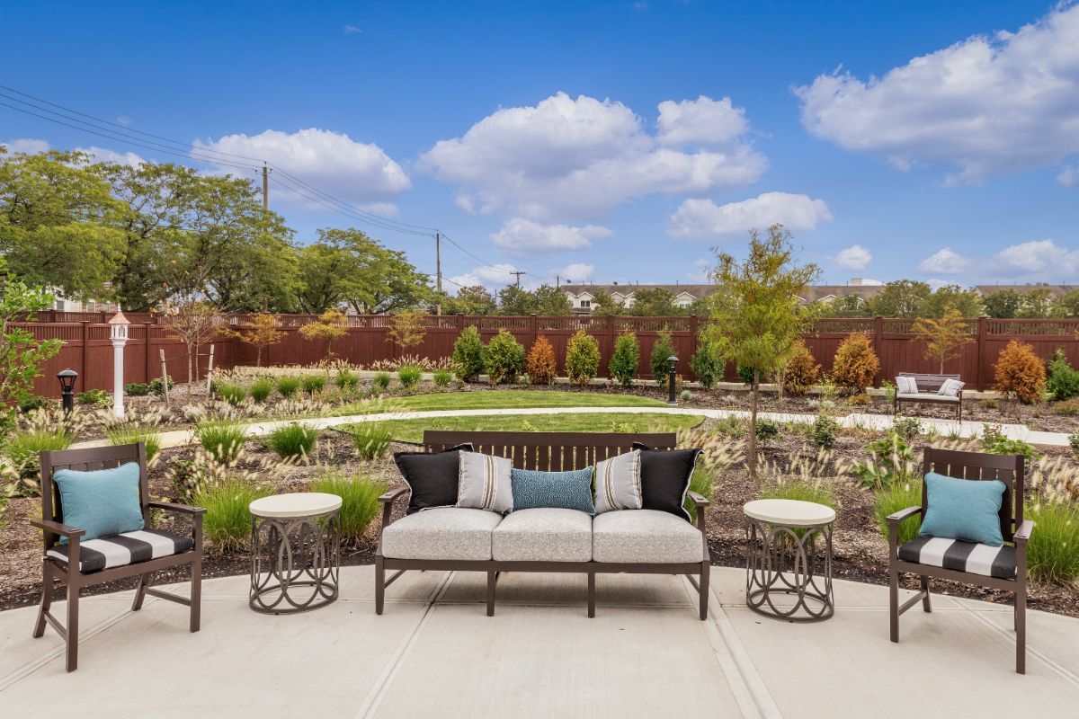 A beautifully landscaped garden with patio seating and clear blue skies.