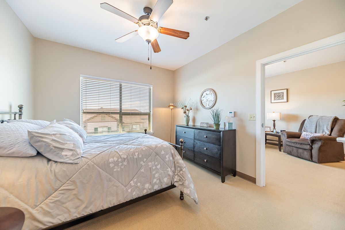 A cozy bedroom with neutral colors, a ceiling fan, and elegant decor.