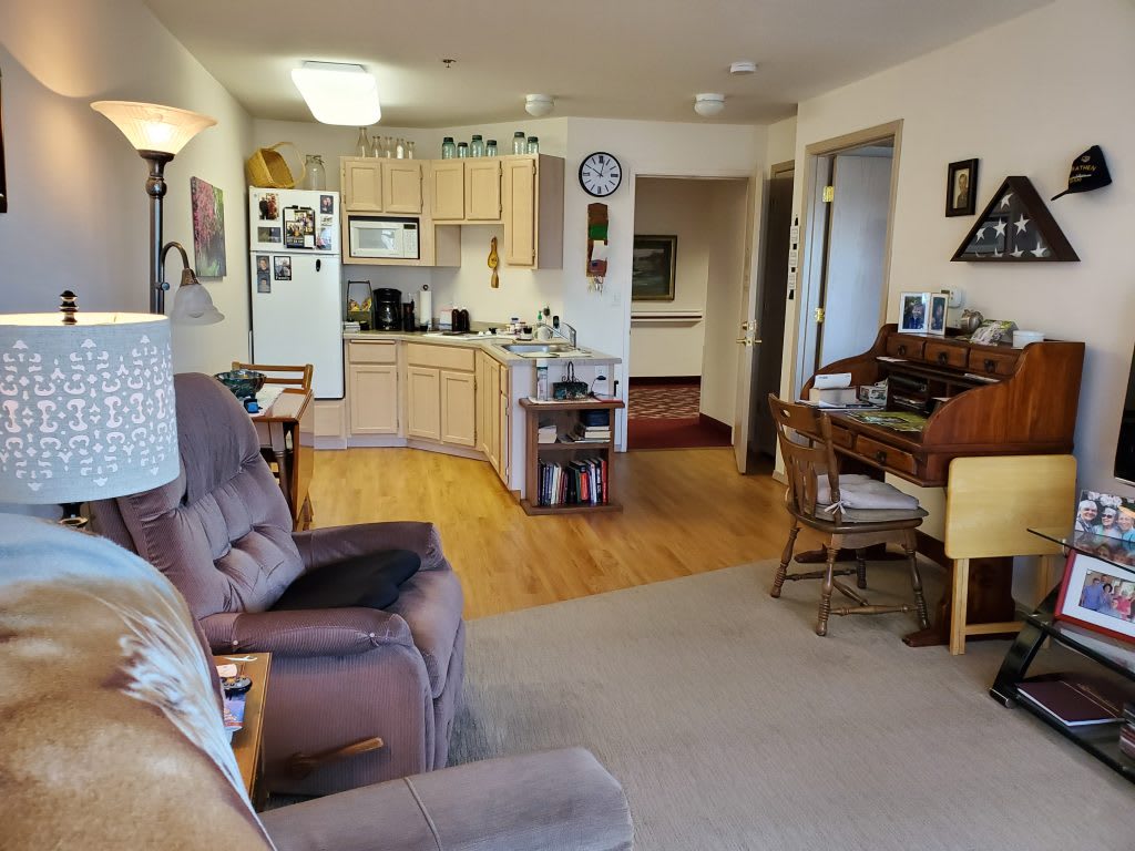 A cozy living space featuring a connected kitchen and seating area with comfortable furniture.