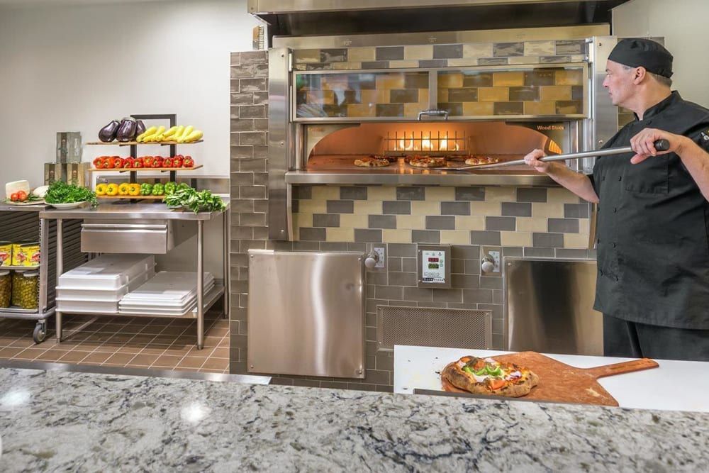 A pizza being prepared in a brick oven kitchen setting.