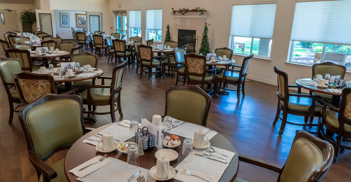A cozy dining area with several tables set for a meal.