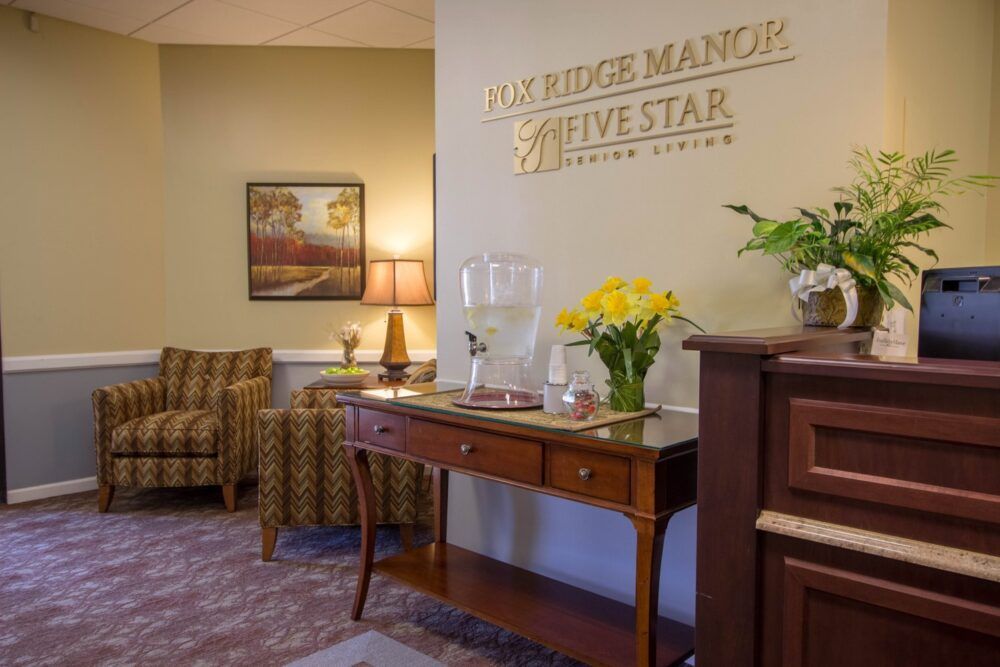 A welcoming lobby area with elegant furniture and decor, featuring fresh flowers and a painting on the wall.