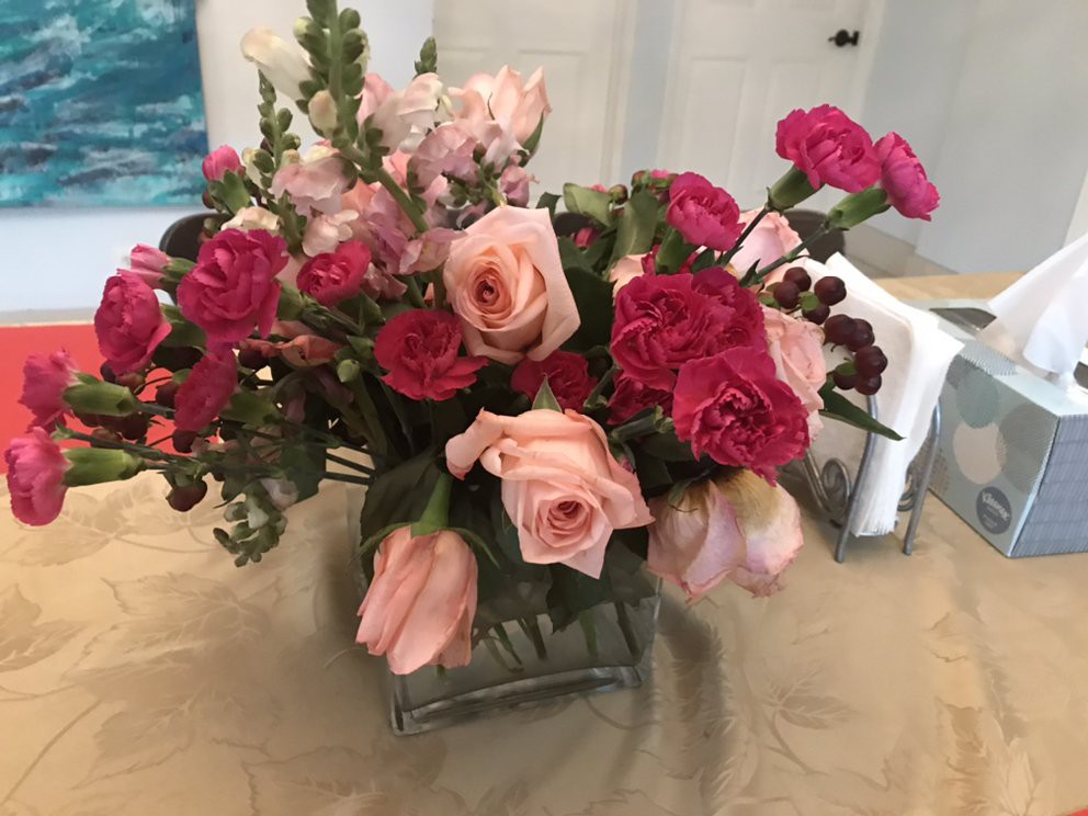 A beautiful floral arrangement featuring pink and red roses and carnations in a glass vase.