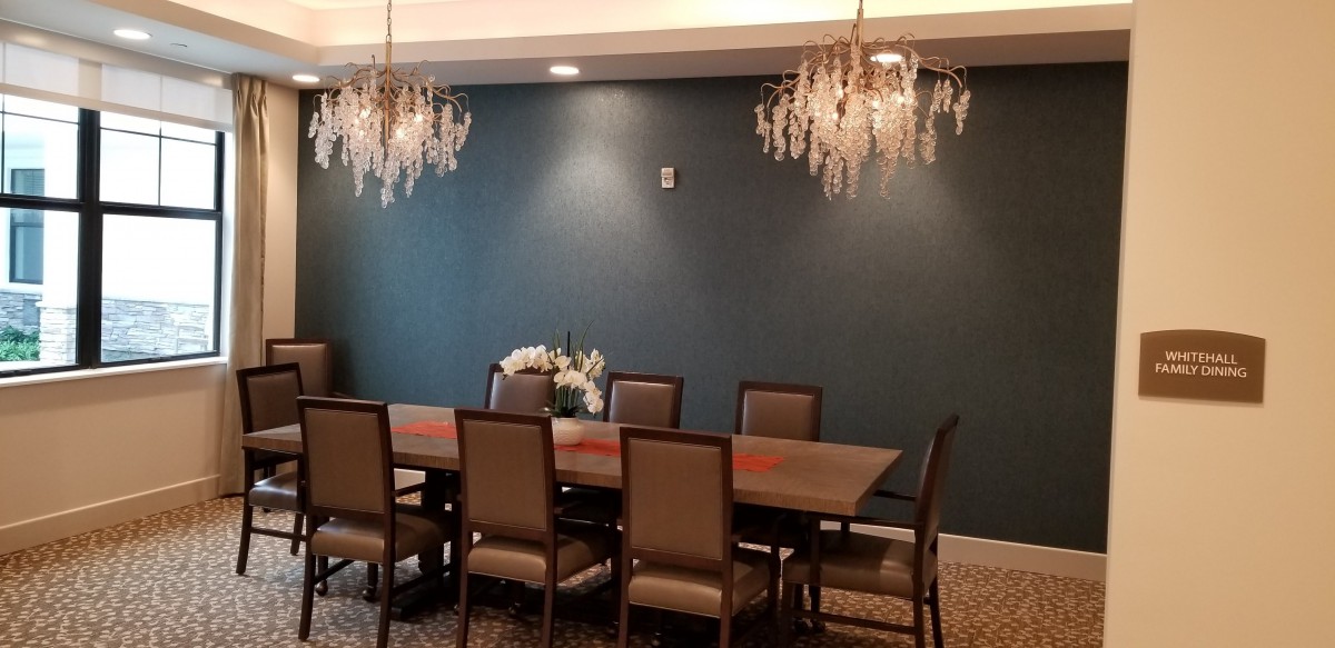 A modern dining room with elegant chandeliers and a long table surrounded by chairs.