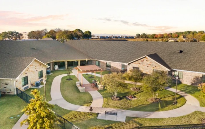 Aerial view of a residential building surrounded by a landscaped garden.