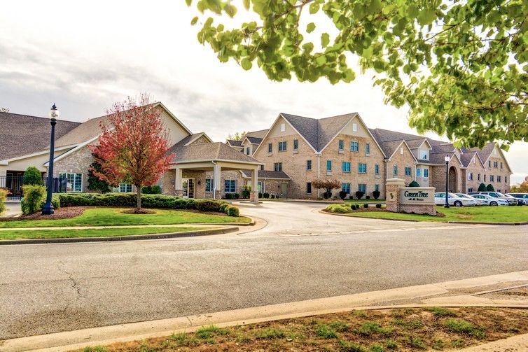 A suburban building surrounded by trees and a road.