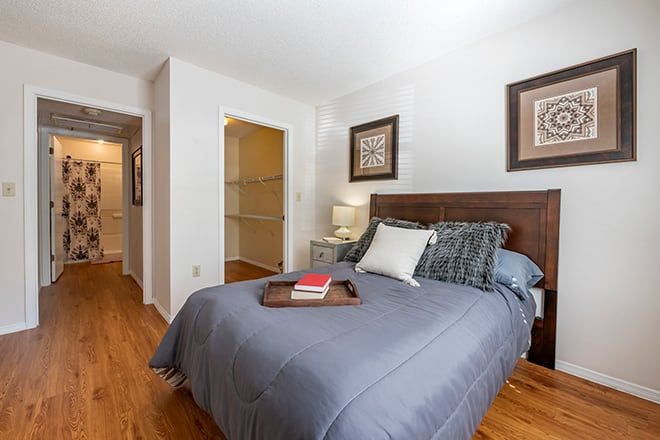 A cozy bedroom with a neatly made bed featuring blue bedding and decorative pillows, complemented by framed artwork on the walls.