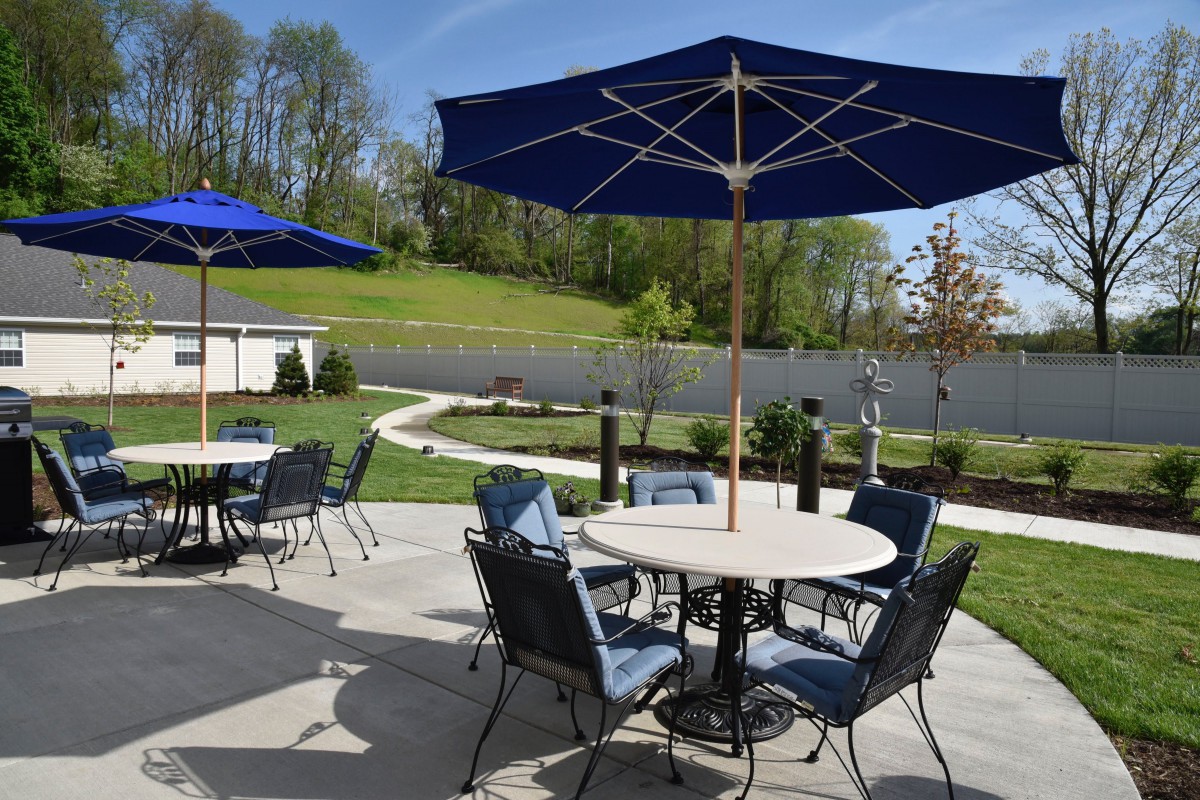 A sunny outdoor patio with tables, chairs, and blue umbrellas.