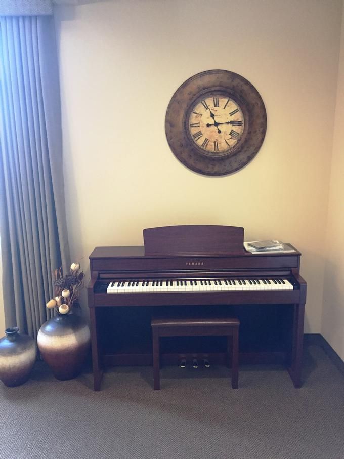 A cozy room with a digital piano, decorative pottery, and a vintage wall clock.