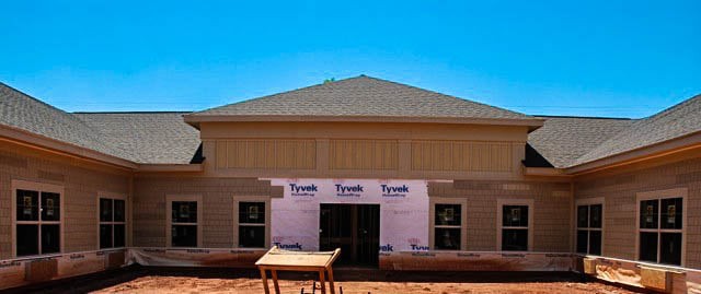 A house under construction with visible siding and roofing.