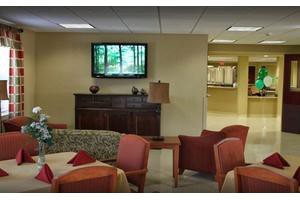 A cozy lobby seating area with comfortable chairs and a television mounted on the wall.