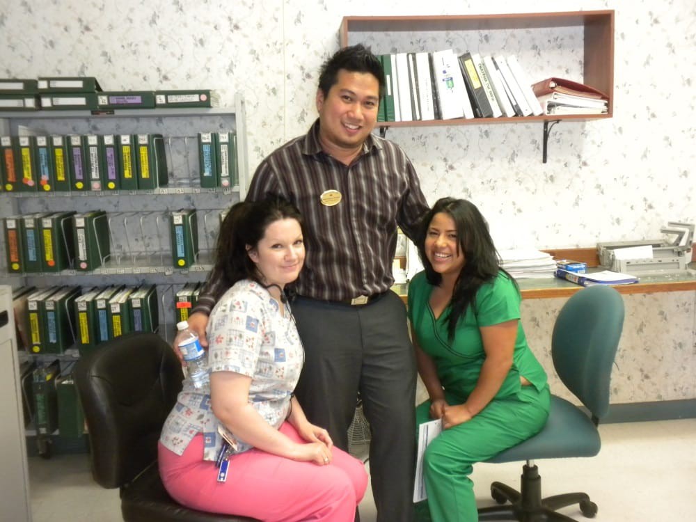 Three people posing together in a workplace setting.