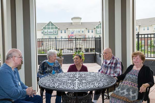 Seniors engage in a lively conversation with their caregiver in a welcoming outdoor space.