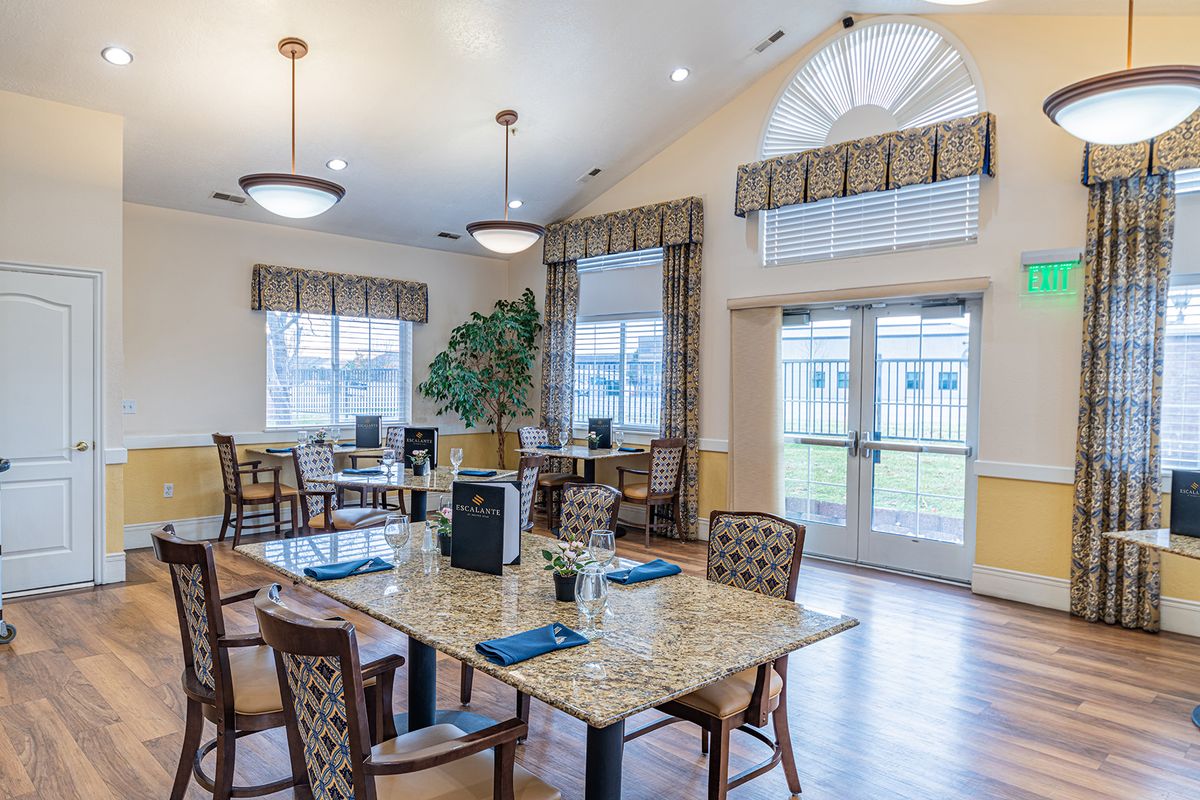 A well-lit dining area with several tables and chairs, featuring large windows and elegant decor.