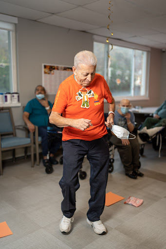 An elderly man participates in a fun activity at a community center, promoting physical movement and social interaction.