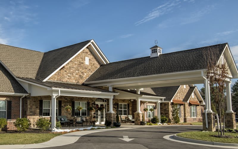A brick residential building with a covered entrance and manicured landscaping.