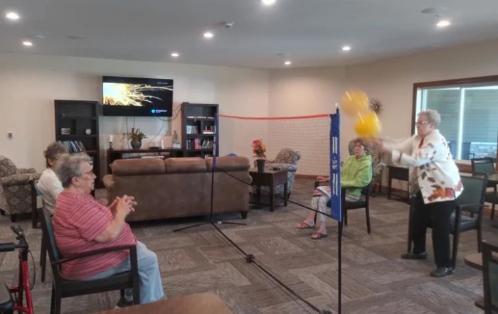 A playful indoor badminton game using a balloon in a living room setting.