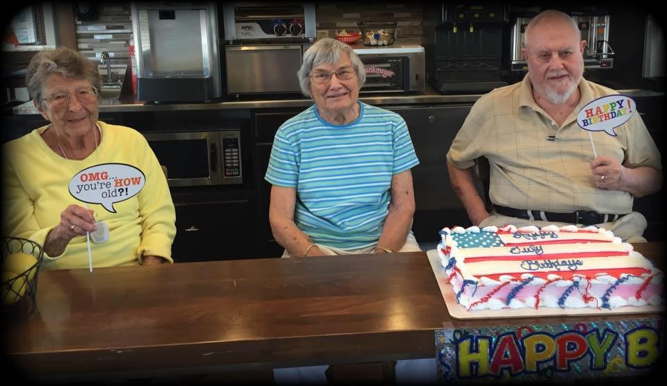 A group of people sitting at a table with a patriotic-themed cake, celebrating an occasion.