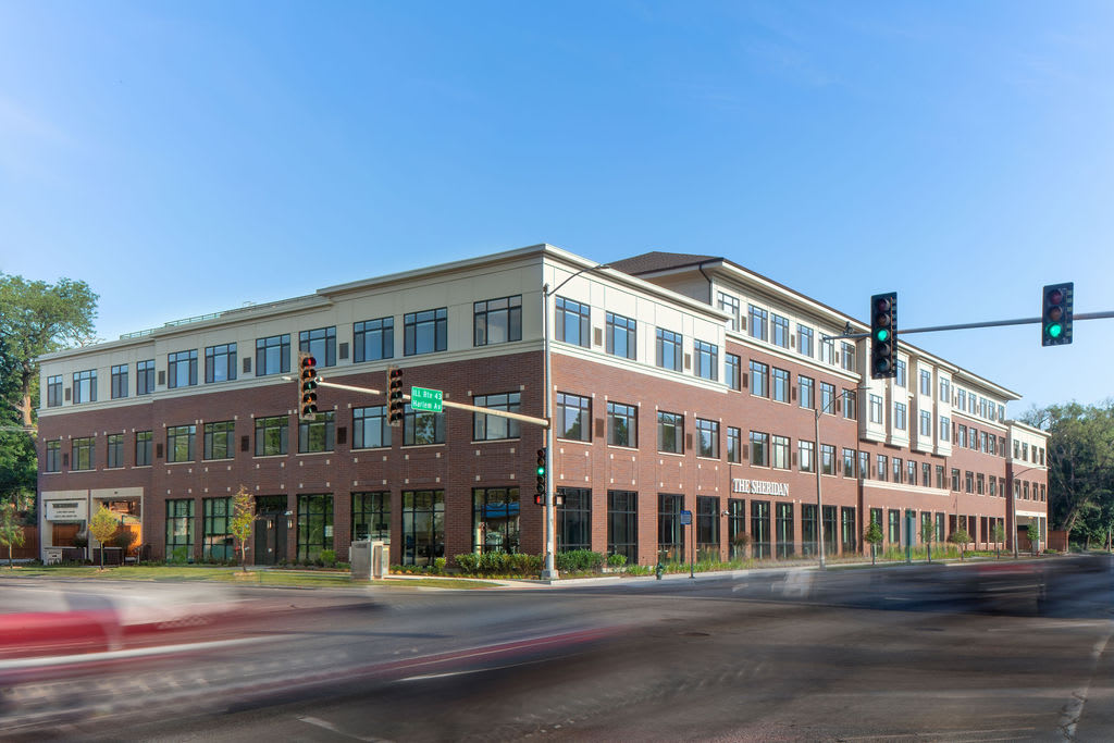 A modern office building at a street corner with traffic lights.