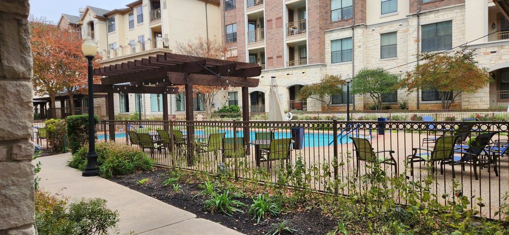 A residential apartment complex with a swimming pool and outdoor seating area.