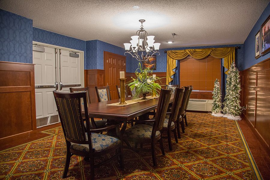 A spacious dining room with a large table, elegant chairs, and a chandelier.