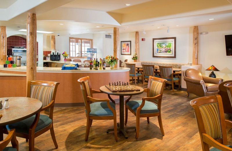A cozy dining area with wooden tables and chairs, decorated with artwork on the walls.