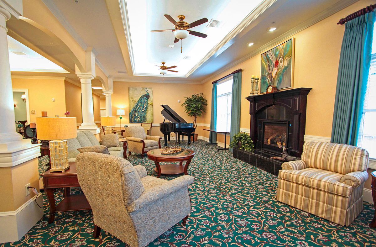 A spacious and elegantly decorated living room featuring a grand piano, fireplace, and comfortable seating.