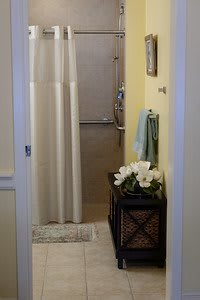 A small bathroom featuring a shower with a curtain, decorated with towels and flowers.