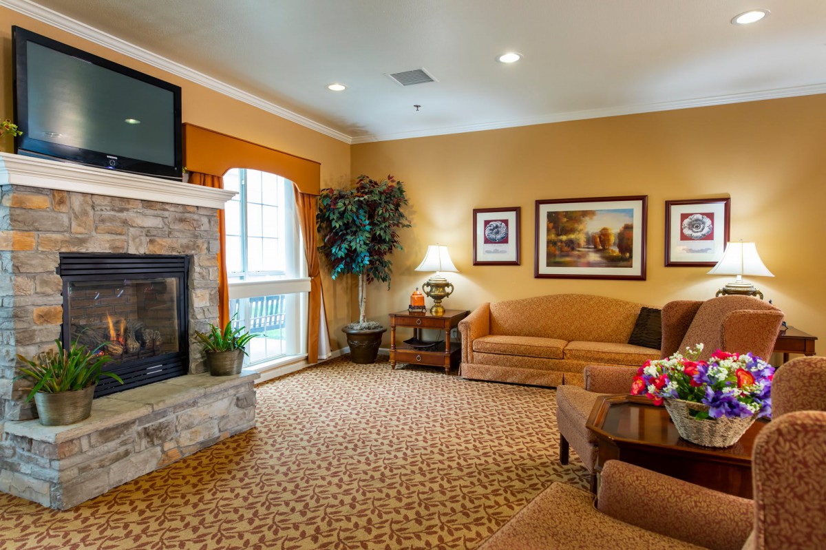 A cozy living room with a fireplace and warm decor, featuring a comfortable sofa and a television.