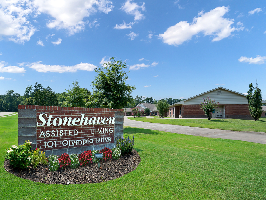 Stonehaven Assisted Living entrance with a manicured lawn and clear sky.