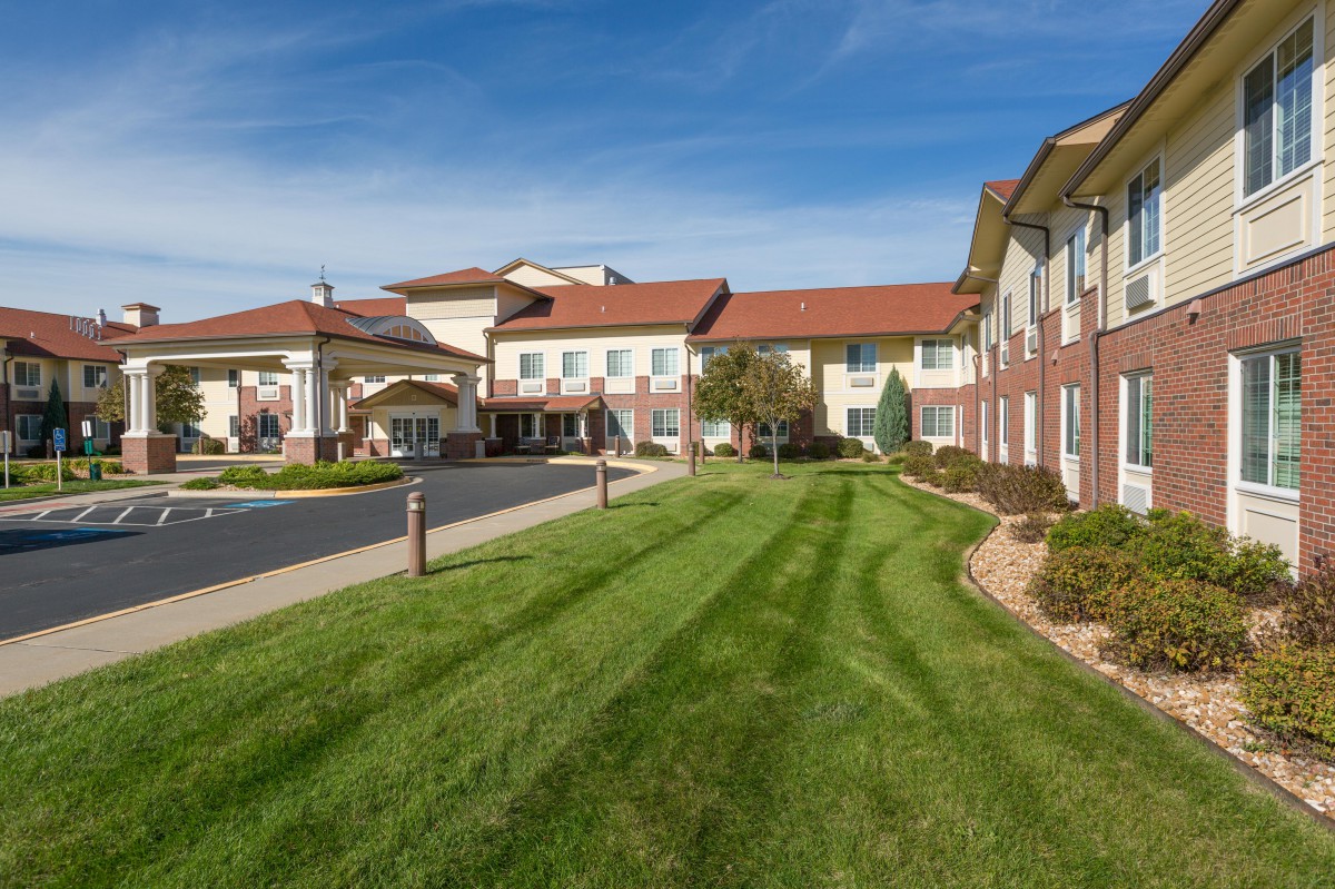 A modern residential building with a well-maintained lawn and clear blue skies.