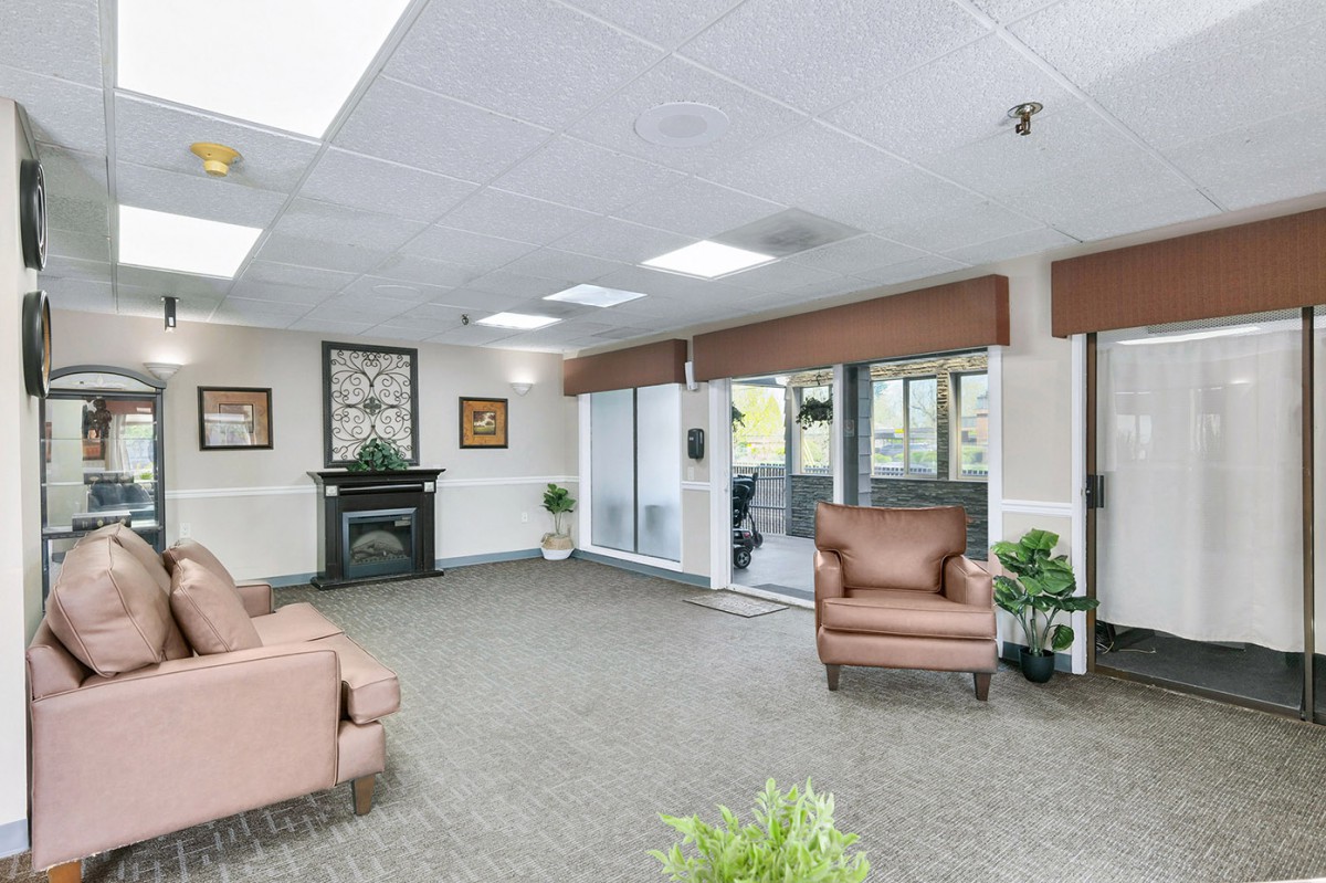 A spacious lobby area with comfortable armchairs, a fireplace, and large windows.