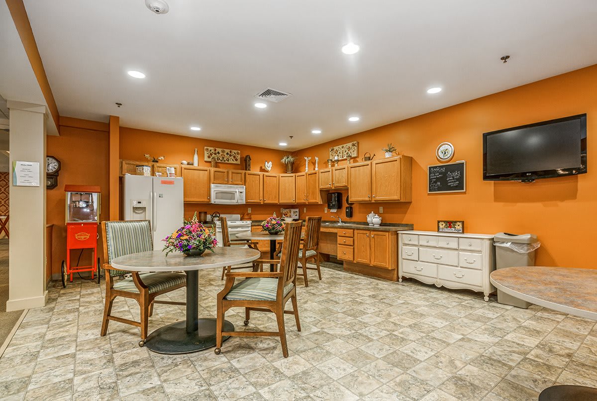 A cozy kitchen and dining area with orange walls, wooden cabinets, and a tile floor.