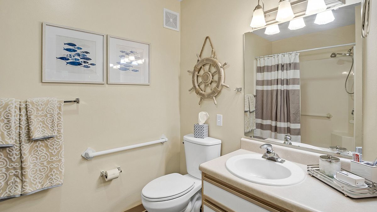 A well-decorated bathroom with nautical-themed decor, featuring a sink, toilet, and mirror.