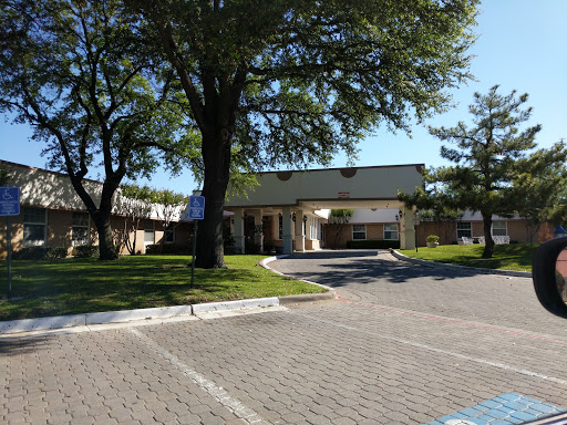 A sunny day showcasing a building surrounded by trees and a neatly paved parking area.