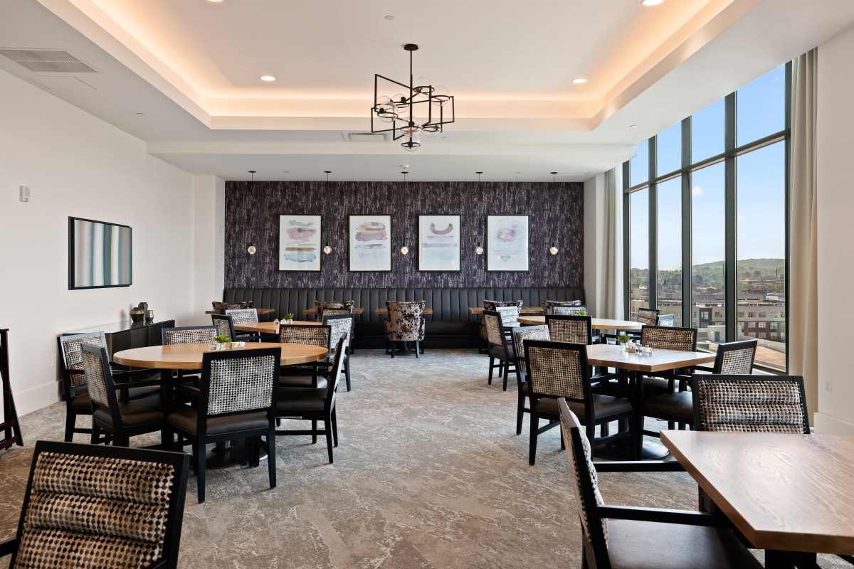 Modern dining area with multiple tables and chairs, featuring large windows and stylish decor.