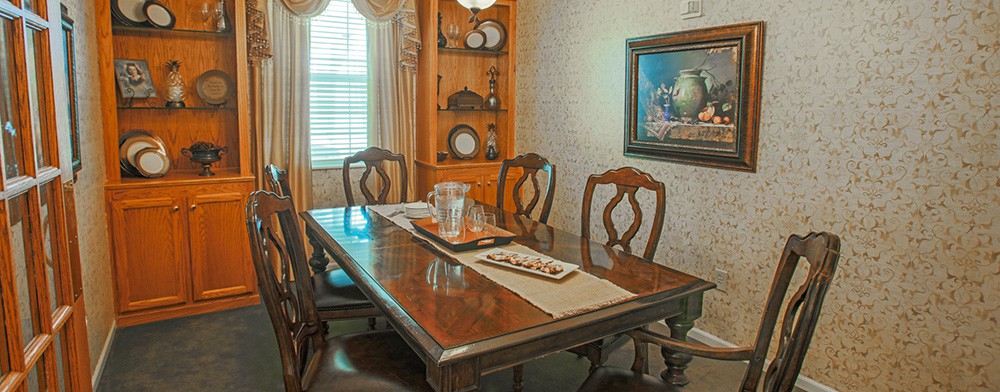 A traditional dining room with a wooden table and chairs, adorned with elegant decor and a framed painting on the wall.