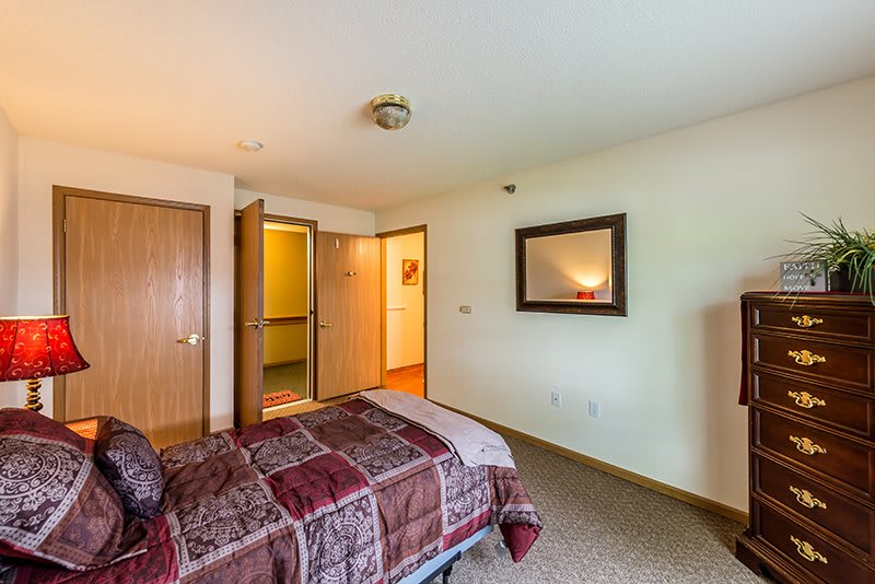 A cozy bedroom with a bed, mirror, and warm lighting.