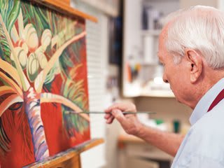 An artist painting a colorful piece on a canvas in their studio.