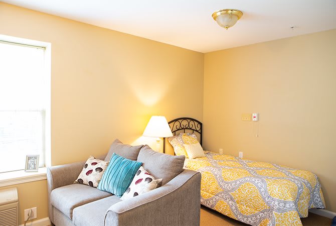 A cozy bedroom with a comfortable couch and a bed with a yellow patterned duvet.