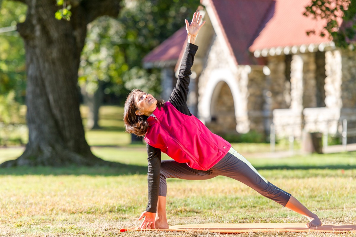 A woman practicing yoga in a park, performing a stretching pose.